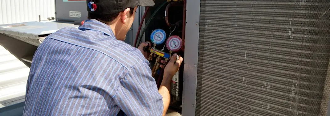 HVAC technician servicing a condenser unit in Itasca