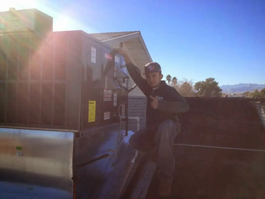 HVAC technician performing Air Duct Cleaning on a rooftop unit in Itasca